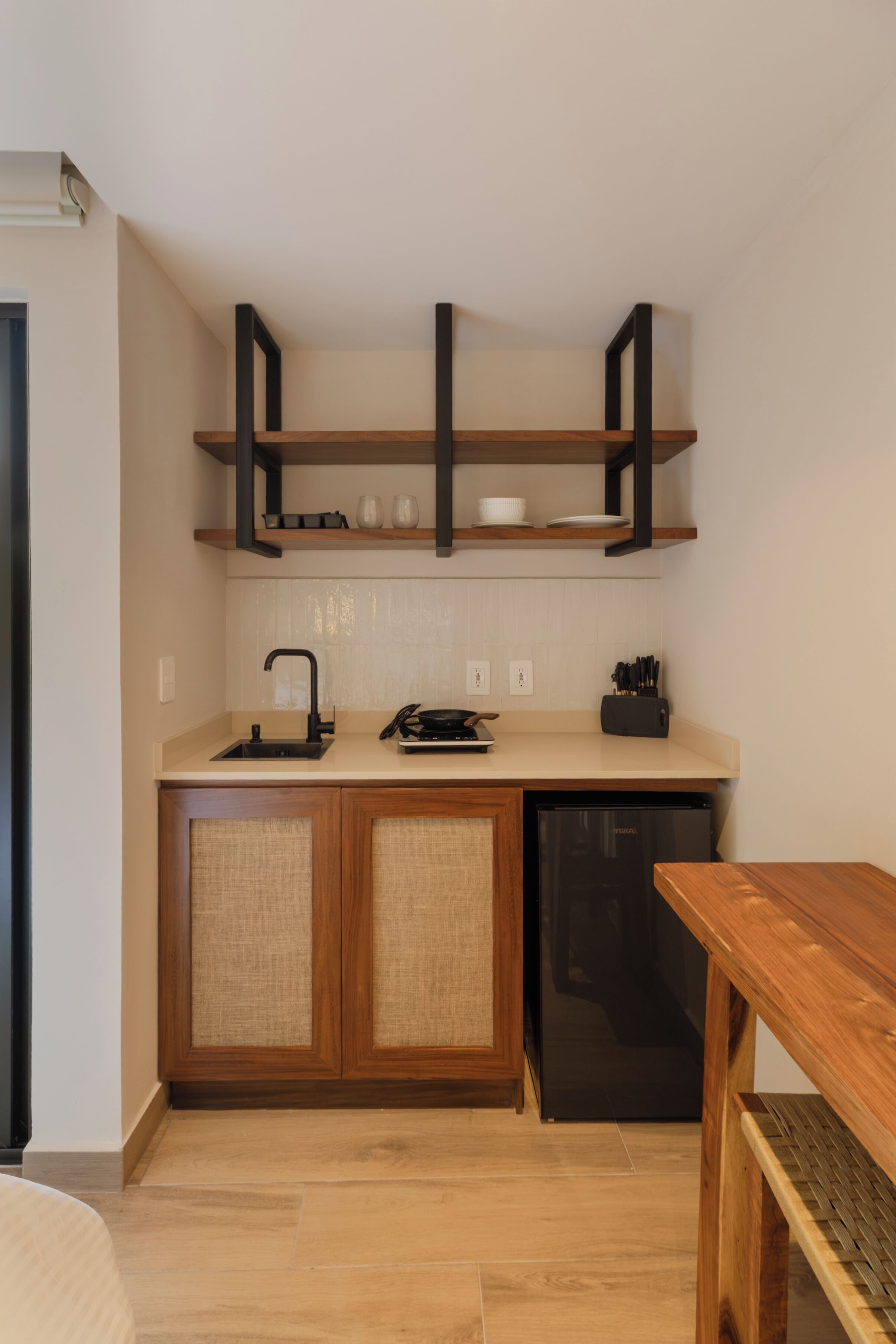 A kitchen with wooden cabinets, a black dishwasher, and a wooden table.