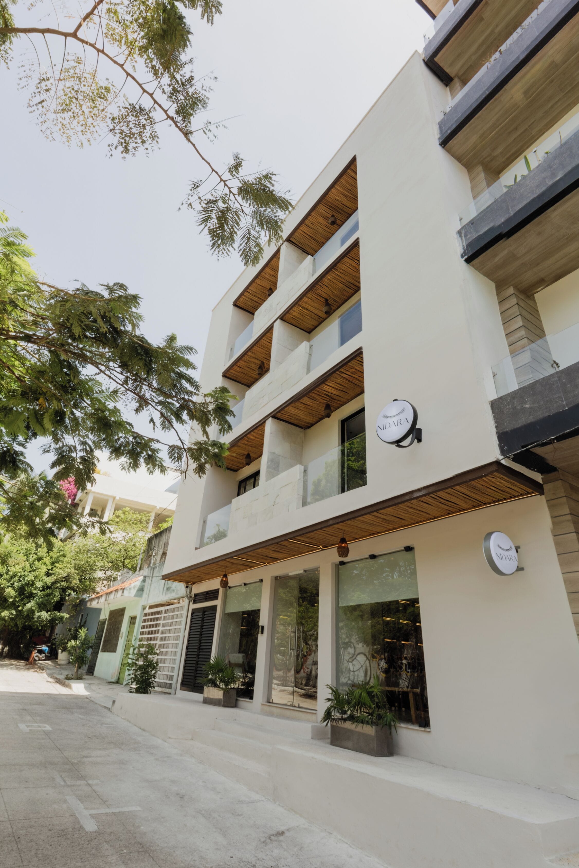 Un bâtiment moderne doté de nombreux balcons, de grandes fenêtres et d’une enseigne sur laquelle on peut lire « NIDARA ».