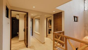 Un interior moderno con una escalera de madera, un pasillo que conduce a un baño y vista a una pared de piedra.