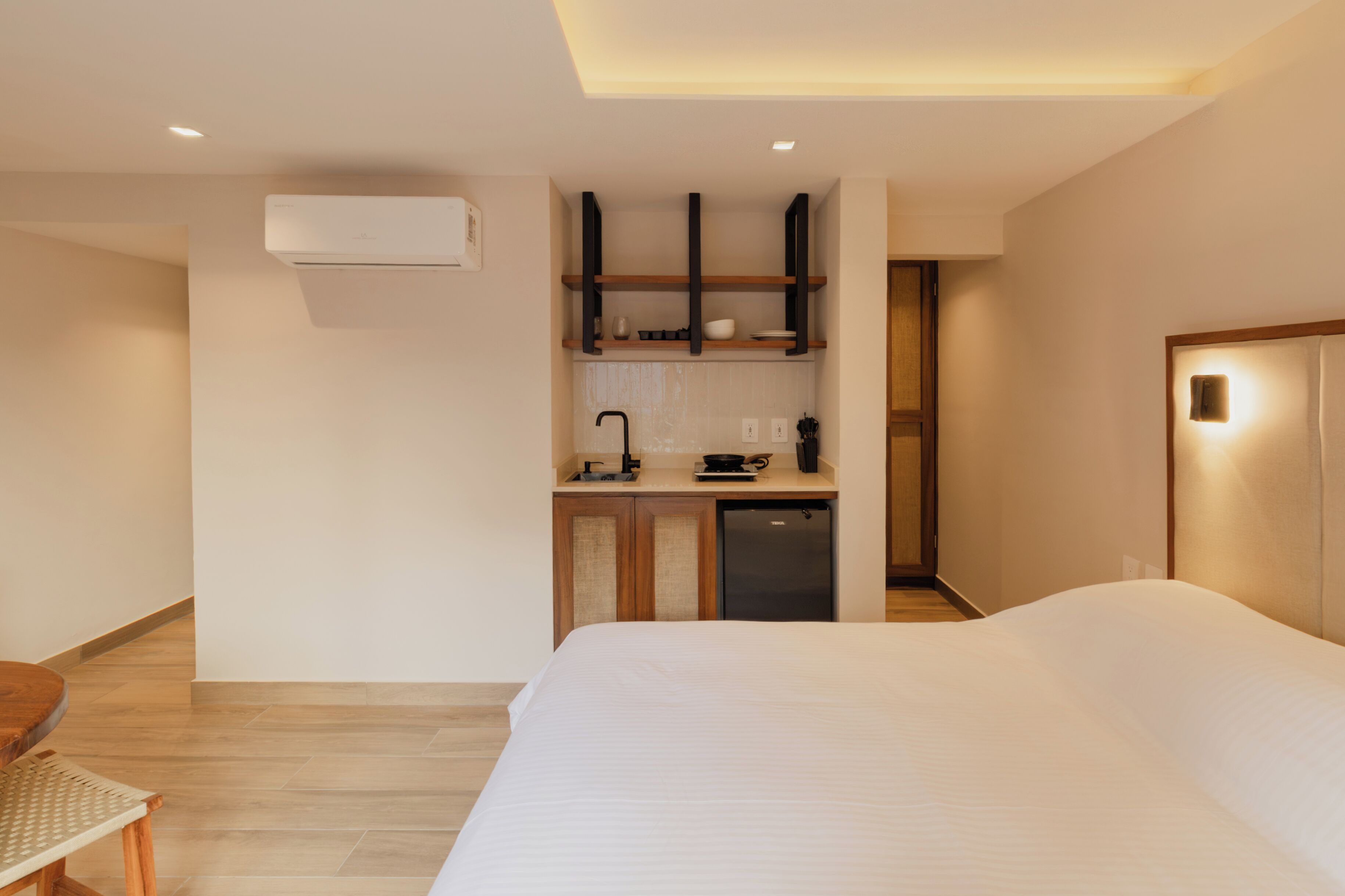 Een moderne hotelkamer met een groot bed, een kleine kitchenette en een aparte badkamer.