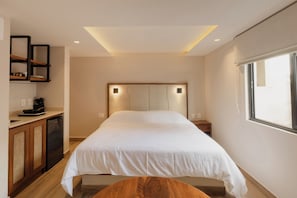 Um quarto com uma cama, mesas de cabeceira, um banco de madeira, uma prateleira embutida e uma janela.