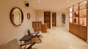Un pasillo con un mostrador de recepción de madera, una sala de espera con sillas y un armario de madera con puertas de vidrio.