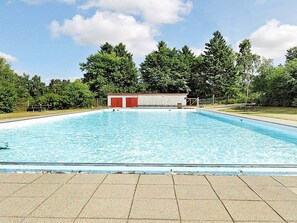 A rectangular swimming pool with a tiled deck in the foreground. - 4 Star Holiday Home in Farvang (Farvang)
