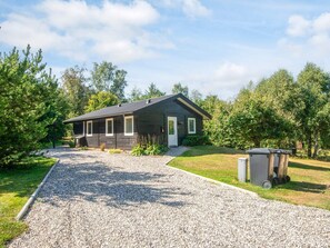 A small, dark-colored cabin with a gravel driveway leading to a wooden door. - 4 Star Holiday Home in Farvang (Farvang)
