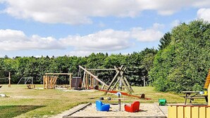 Ein Spielplatz im Freien mit Schaukeln, Rutschen und Klettergerüsten.