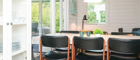 A dining area with a table and chairs, a pendant light, and a view of greenery outside.