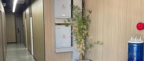 Un pasillo con dispensador de agua, un banco y una planta en maceta.