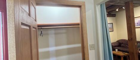 Una habitación con puerta de madera, techo con vigas a la vista, una ventana y un sofá.