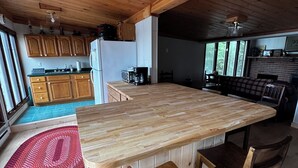 Una cocina de madera con una isla grande, armarios de madera y un tapete tejido rojo.