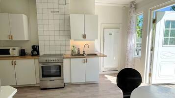 A compact kitchen with white cabinets, a stainless steel stove, and a microwave.
