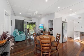 A modern living room with a dining area, a kitchen, and a balcony with a view. - Verney Beachside Getaway (Kings Beach)