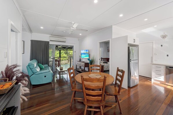 A modern living room with a dining area, a kitchen, and a balcony with a view. - Verney Beachside Getaway (Kings Beach)