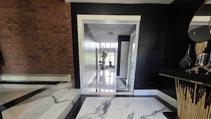 Un intérieur moderne avec un sol en marbre, un mur en briques et un panneau décoratif noir et doré.