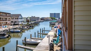 Een jachthaven met aangemeerde boten, een houten steiger en gebouwen langs het water.
