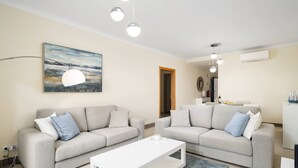 Ein modernes Wohnzimmer mit zwei grauen Sofas, einem weißen Couchtisch und einem Bild an der Wand.