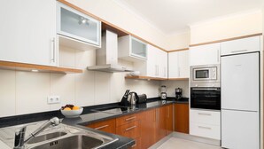 Eine moderne Küche mit Edelstahlgeräten, Holzschränken und einer schwarzen Arbeitsplatte.