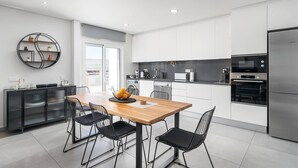 Una cocina moderna con zona de comedor, que incluye un refrigerador Bosch, un microondas y un lavavajillas.