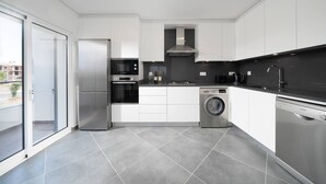 A modern kitchen with stainless steel appliances, a built-in oven, a washing machine, and a dishwasher. - Rare & Modern Conceição e Cabanas Apartment (Tavira)