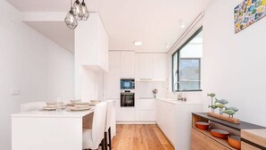 Una cocina moderna con armarios blancos, una mesa de comedor de madera y un ventanal con vistas.