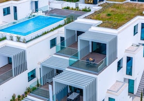 A modern multi-story building with a rooftop pool, glass balconies, and a flat roof garden. - Spectacular Ria View Fuseta Apartment (Olhão)