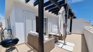 A rooftop terrace with a grill, wicker furniture, and a covered seating area. - Stylish Tavira Apartment (Tavira)