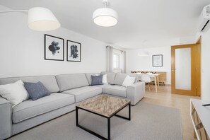 Ein modernes Wohnzimmer mit einem grauen Sofa, einem Couchtisch und Kunstwerken an der Wand.