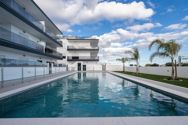 A modern building with a swimming pool, multiple balconies, and a clear sky. - Sunset View Apartment in Conceição de Tavira (Tavira)