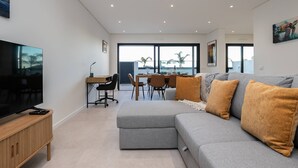 Een moderne woonkamer met een grijze modulaire bank, een flatscreen televisie en een houten tv-meubel.