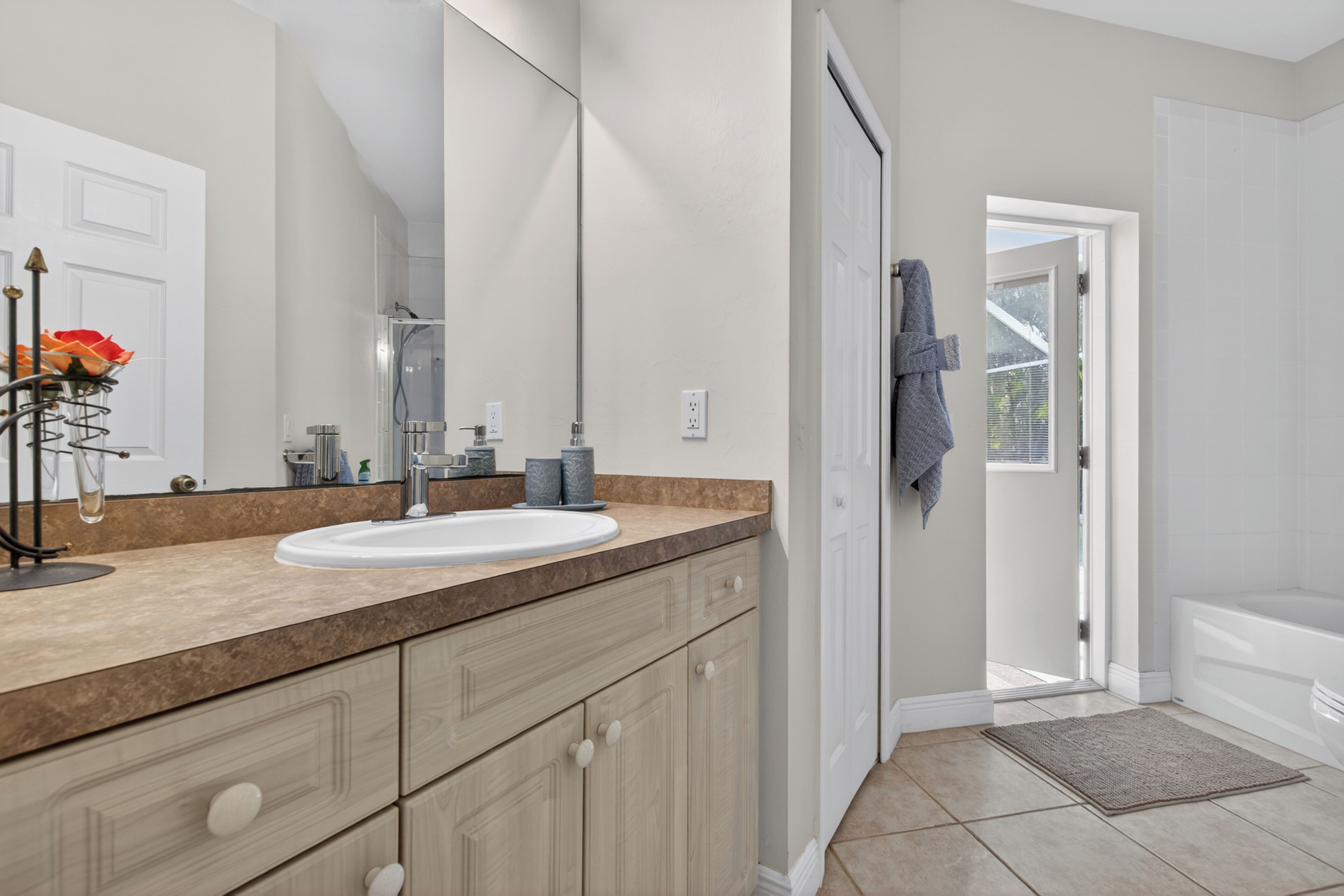 Une salle de bain équipée d’un lavabo, d’un miroir, d’un porte-serviettes et offrant une vue sur l’extérieur.