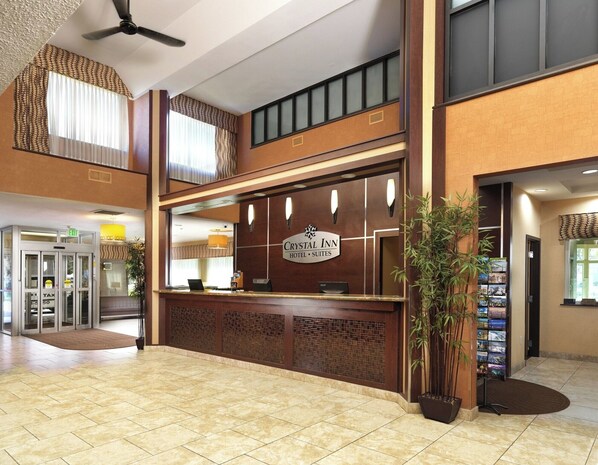 En hotellobby med en skylt som visar texten ”Crystal Inn Hotel Suites”. Här finns en receptionsdisk, en kassa och en växt nära ingången.