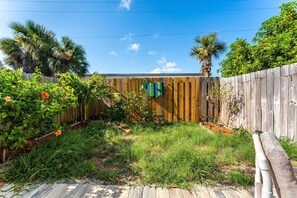 Ein Garten mit Holzzaun, verschiedenen Pflanzen und einer Holzterrasse.