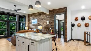 Una cocina moderna con una isla de mármol, paneles de madera en la pared y un comedor con sofá y mesa.