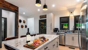 Una cocina moderna con una isla de mármol, electrodomésticos de acero inoxidable y una botella de vino.