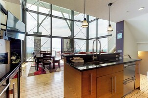 Una cocina moderna con una isla grande, armarios de madera y vistas amplias a través de ventanas grandes.