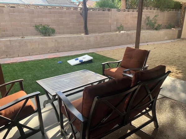 An outdoor patio with a table and chairs, a small patch of artificial grass, and a brick wall in the background. - Relaxing Retreat - 5 miles from strip! (Henderson)