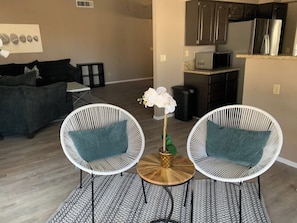 A living room with two white wicker chairs, a small round table, and a potted orchid. - Relaxing Retreat - 5 miles from strip! (Henderson)