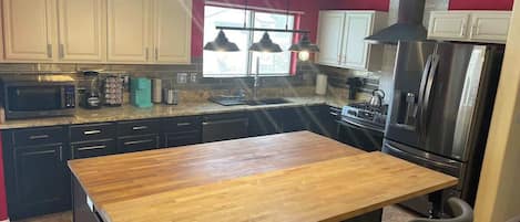 A kitchen with a wooden island, stainless steel appliances, and a window with natural light.
