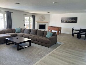 Ein Wohnzimmer mit einem Ecksofa, einem Couchtisch, einem Kamin und einem Essbereich mit Tisch und Stühlen.