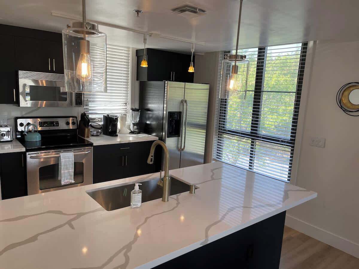 Una cocina moderna con electrodomésticos de acero inoxidable, encimera de mármol e iluminación colgante.