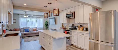 A modern kitchen with white cabinetry, stainless steel appliances, and a central island.