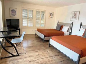 A room with two beds, a desk with a TV, and a chair. - Location, Location, Location! (Las Vegas)