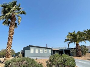 Ein eingeschossiges Gebäude mit flachem Dach, einer Garage und wolkenlosem, blauem Himmel.