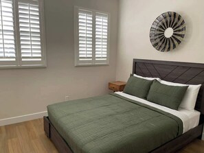 A bedroom with a bed, a nightstand, a wall clock, and two windows with blinds. - Private Outdoor Oasis 2 (Henderson)