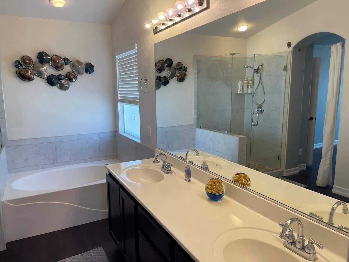 Une salle de bain avec deux lavabos, un grand miroir et une douche.
