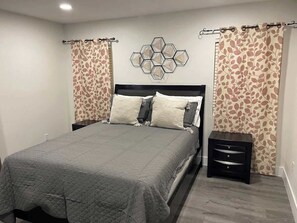 A bedroom with a bed, nightstands, and a wall-mounted decorative piece. - Warm and Welcoming Retreat with Pool (North Las Vegas)