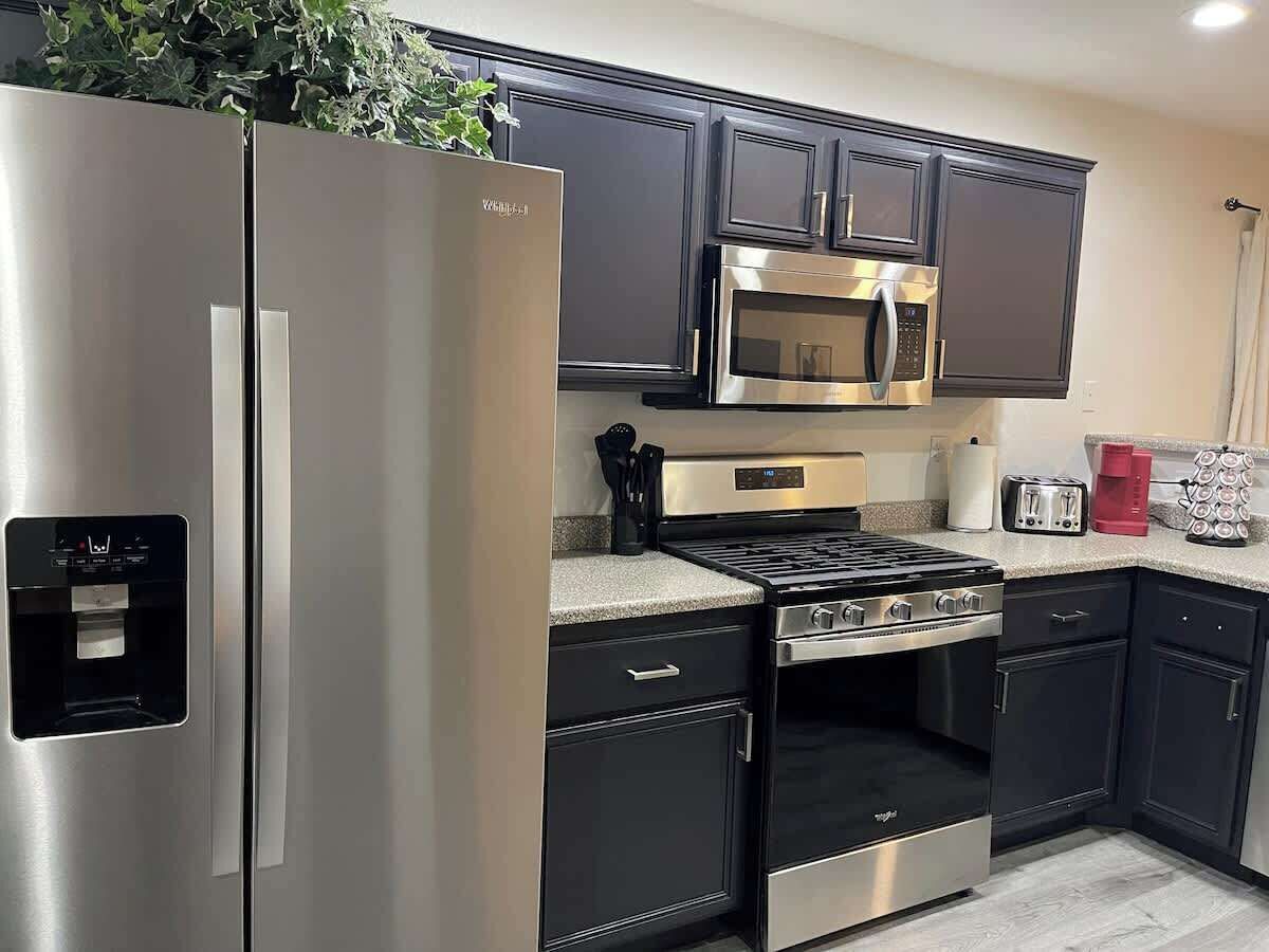 A modern kitchen with stainless steel appliances, dark cabinetry, and a built-in microwave.