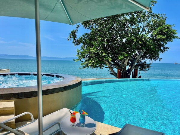 A pool area with a hot tub, lounge chairs, and a table with drinks. - Beachfront condo | Beautiful with amenities (Bucerías)