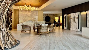 A spacious lobby with a high ceiling, a central seating area with wicker chairs, a marble reception desk, and a modern chandelier. - Beachfront condo | Beautiful with amenities (Bucerías)