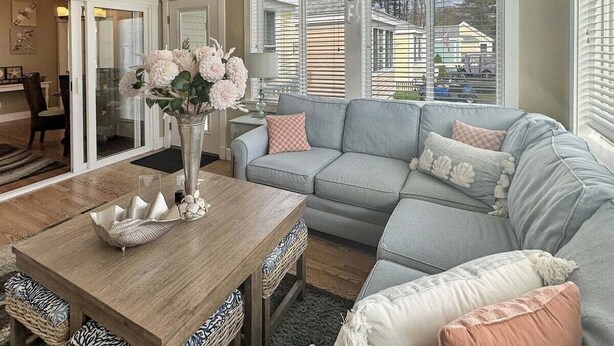 A living room with a grey sofa, a wooden coffee table, and a vase with flowers. - Seaglass Village 225 - Beach House (Wells)