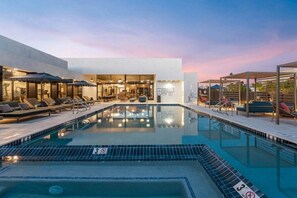 Un hotel moderno con piscina, zona de descanso y restaurante.